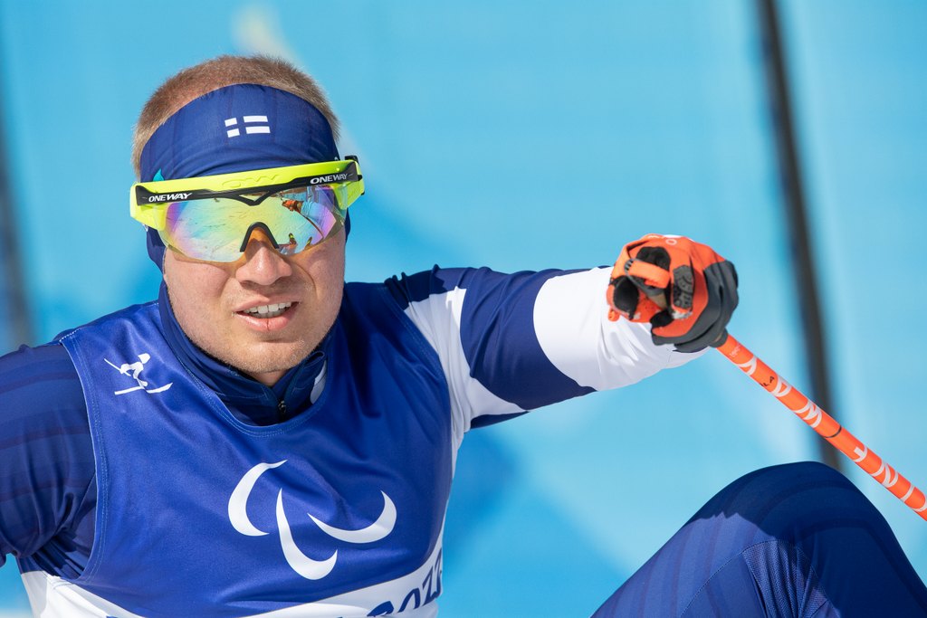 Inkki Inola istumassa hiihtosuorituksensa jälkeen hymyillen maassa.